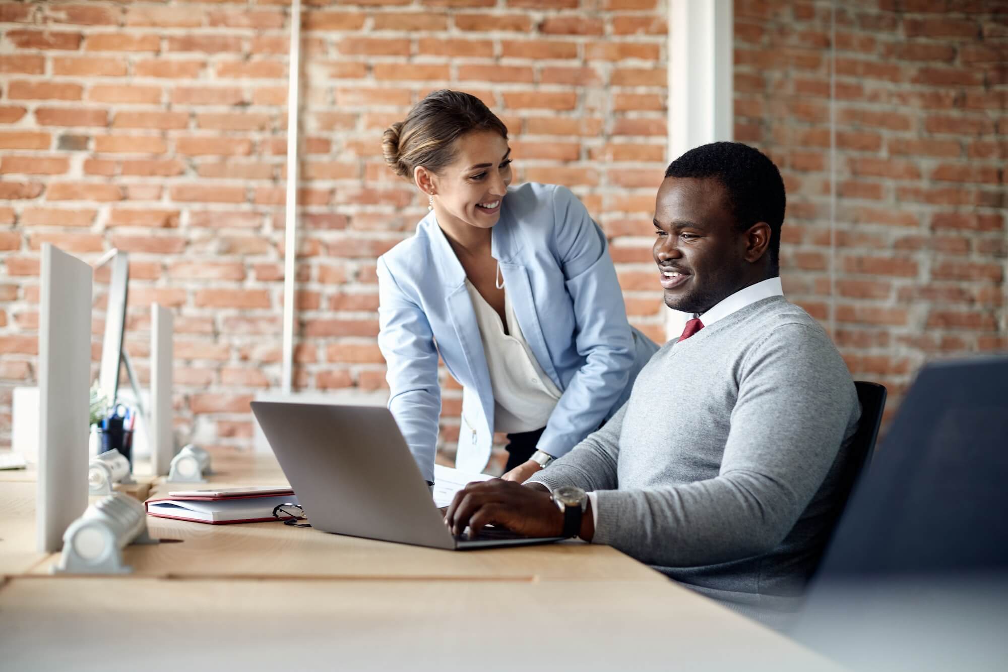 Happy colleagues cooperating while working on a computer in the office.